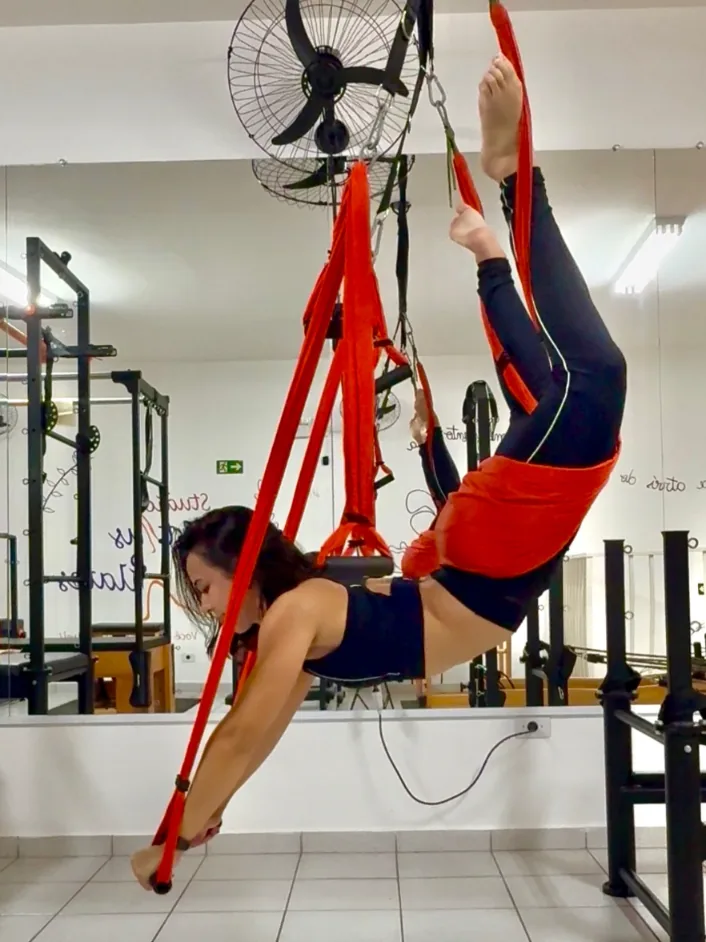 Aula de pilates com tecido aéreo vermelho no espaço do Studio Fortius